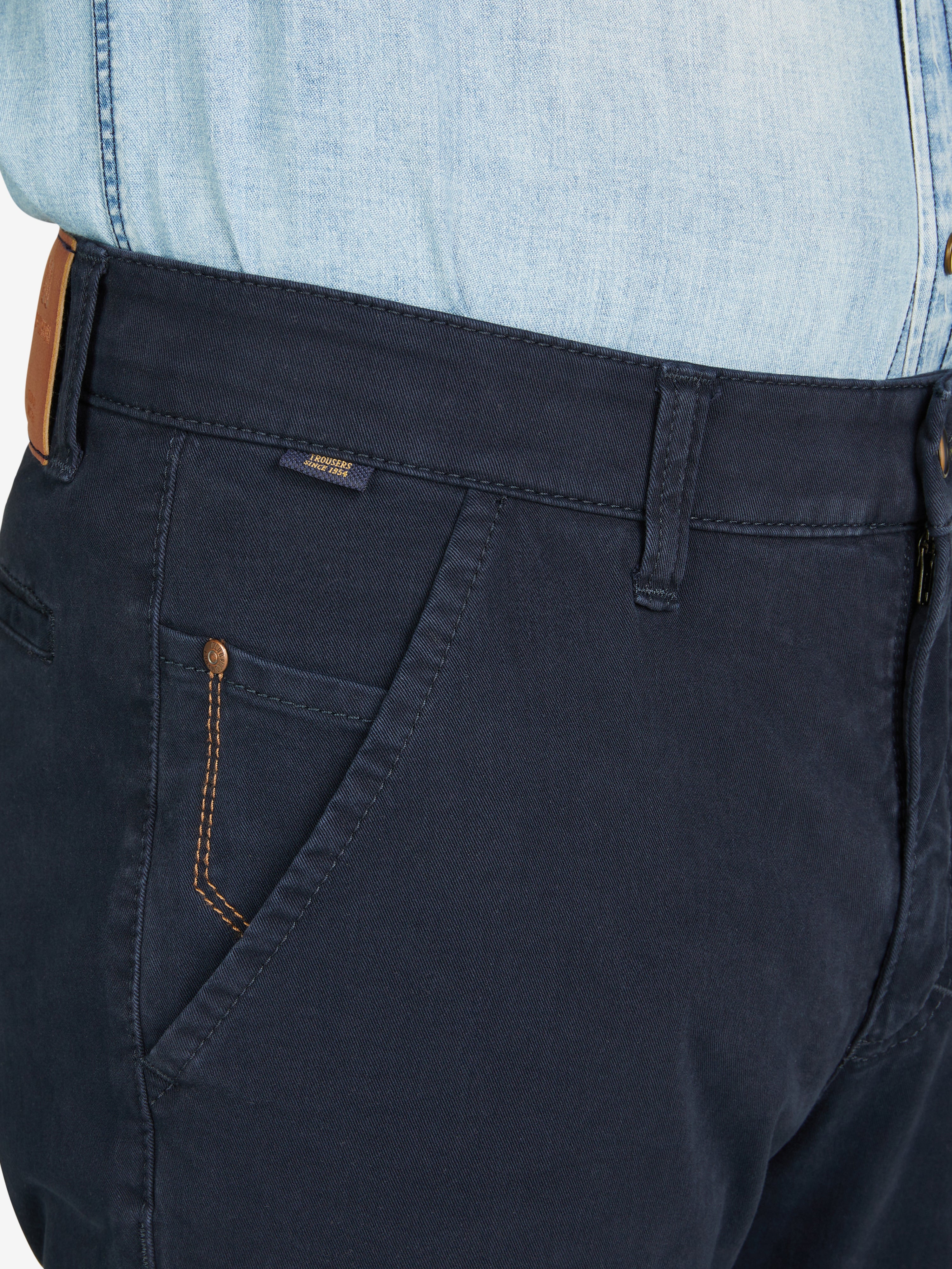 Nahaufnahme einer dunkelblauen GARVEY 8070 Flat Front-Hose mit elastischem Komfortbund, Hemdstopper und Münztasche, gefertigt aus bi-elastischer Baumwolle. Die Hose hat eine normale Leibhöhe, schmal zulaufenden Beinverlauf, und zeigt Details wie kontrastfarbene Steppnähte und Safety-Pocket.