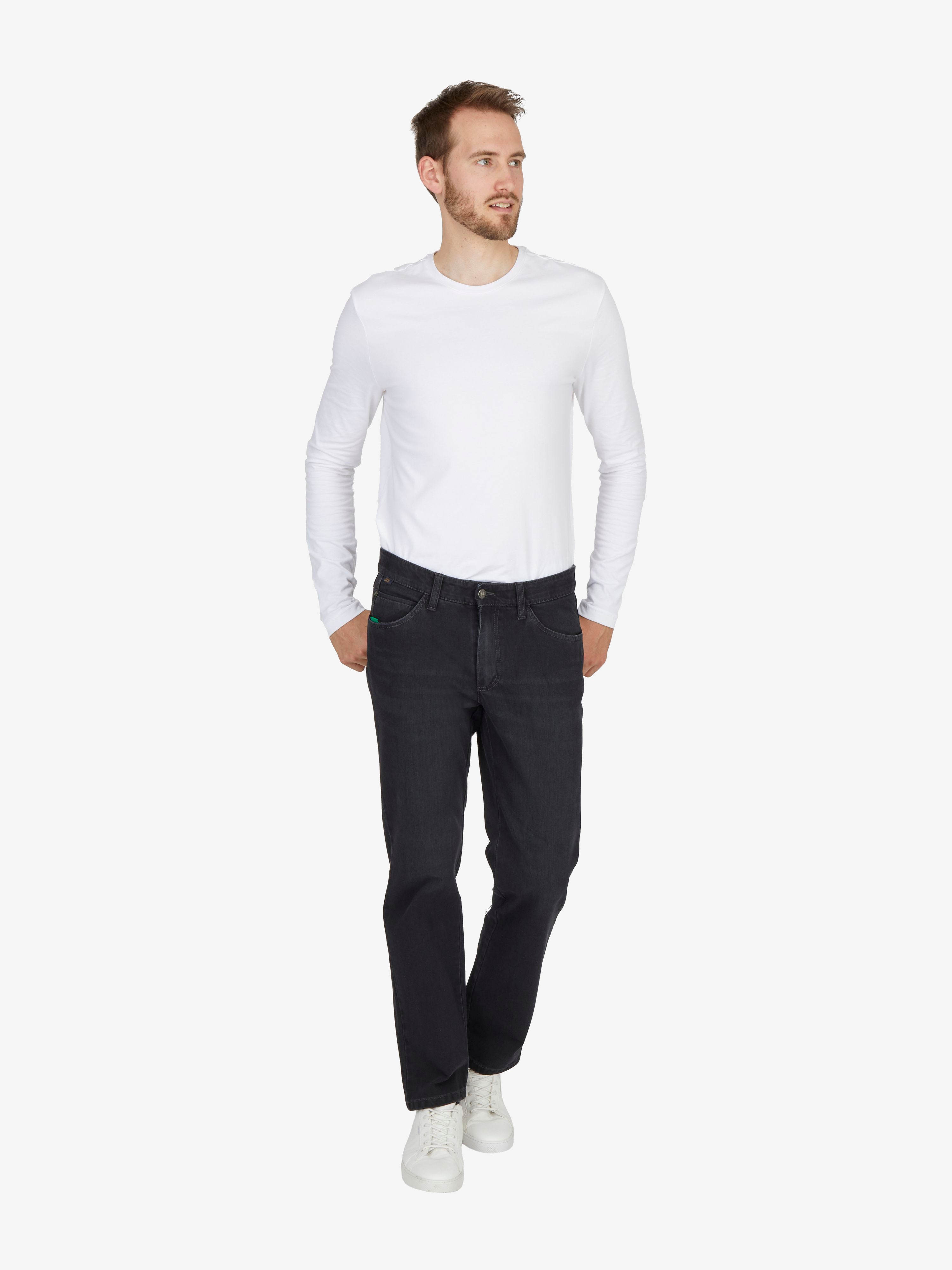Mann in weißem Langarmshirt und schwarzen HENRY 7054 Jeans mit elastischem Bi-Stretch-Denim, 6-Pocket-Design, Mobile Pocket, Komfortbund, Regular Fit, schwarz, ganzjährig, model in Bewegung vor neutralem Hintergrund.