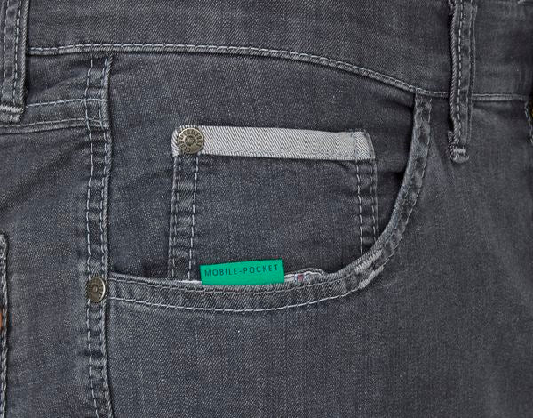 Nahaufnahme eines Jeanshosenbundes mit einer kleinen, grünen Etikette mit der Aufschrift "MOBILE POCKET" neben der Münztasche, sichtbar sind auch Nationalpinnenknöpfe und graues Nähgarn.