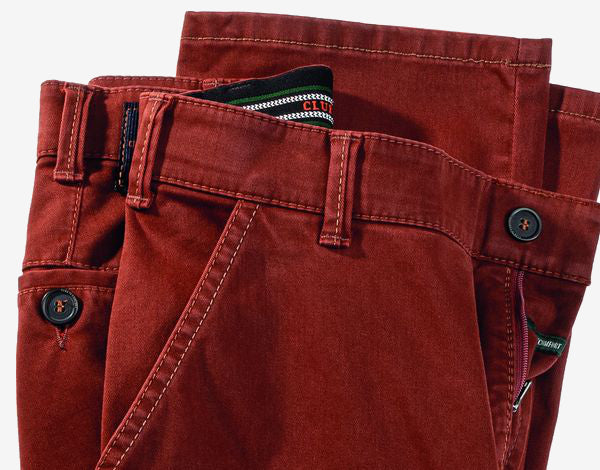 Nahaufnahme von rotbraunen Chino-Hosen, die einen Teil der Gürtel, die Knöpfe, Gürtelschlaufe und den oberen Bereich der Taschen zeigen.