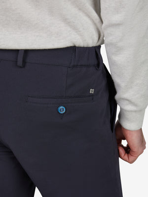 Nahaufnahme einer dunkelblauen, slim-fit Chino-Hose von Club of Comfort mit elastischem Smokbund, Hemdstopper, mittlerer Leibhöhe, einer luxuriösen Mikrofaser-Struktur, einer Blauen Knopfleiste, einer hinteren Gesäßtasche und einem Logo-Tag.