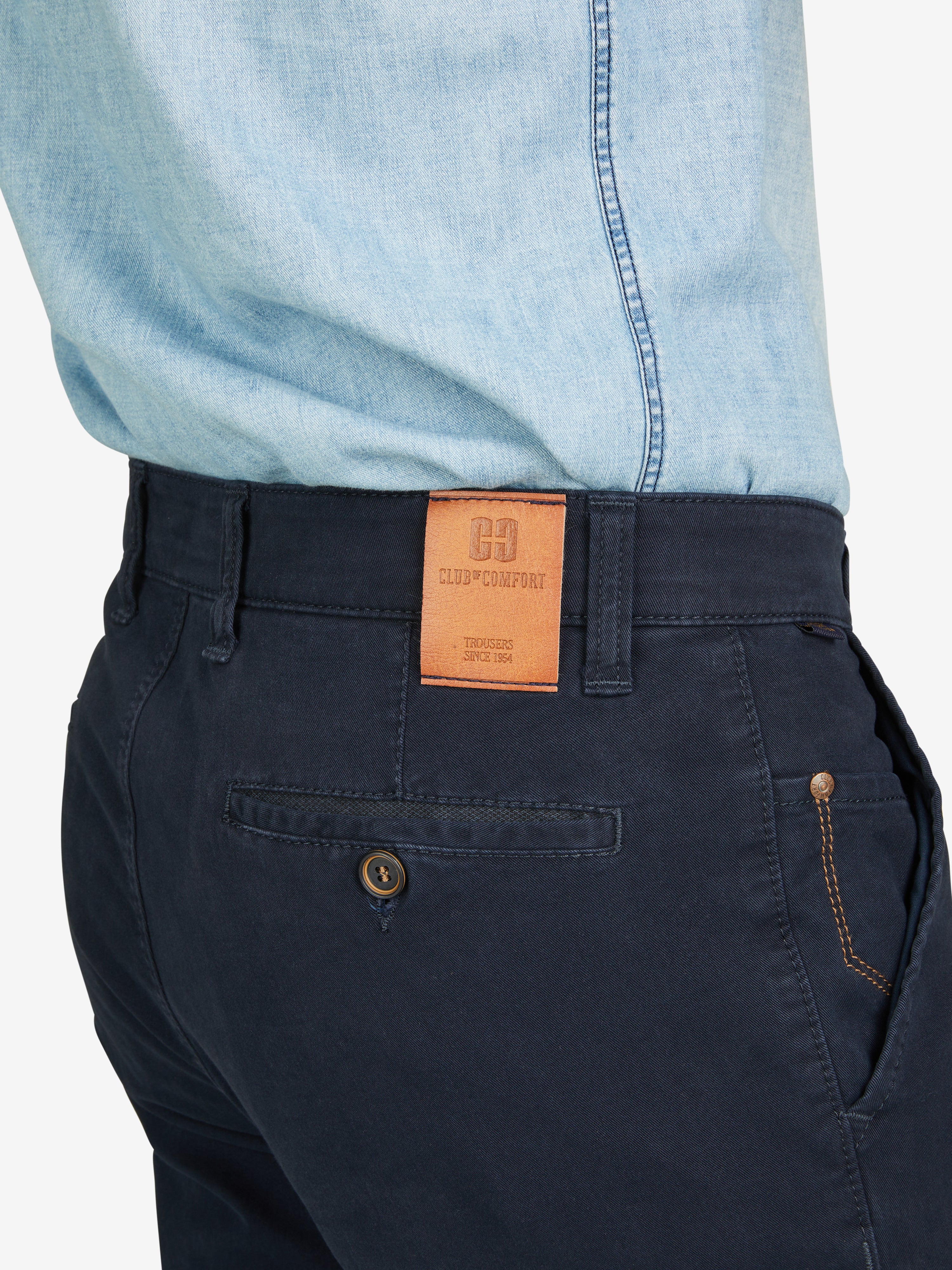 Nahaufnahme einer dunkelblauen Garvey 8070 Flat Front-Hose mit elastischem Komfortbund, Hemdstopper und Safety-Pocket, getragen von einem Model in hellblauem Hemd. Die Hose ist aus bi-elastischer Baumwolle gefertigt, hat eine normale Leibhöhe, schmalere Fußweite und ist für alle Jahreszeiten geeignet.