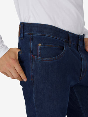 Nahaufnahme einer Person in jeansblauer Hose „MARVIN 7054“ von Club of Comfort, mit elastischem Komfortbund, Swing-Pocket, modifizierte 5-Pocket-Form, Regular Fit, aus hochelastischem Bi-Stretch-Denim mit T400-Beimischung, formstabil, kurz, ganzjährig, blaue Farbfamilie.