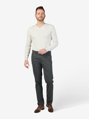 Mann trägt eine graue MARVIN 8025 Thermohose mit elastischem Comfortbund, Swing-Pocket, doppelt paspelierter Münztasche und Thermolite-Wärmeisolierung, kombiniert mit einem weißen Pullover. Die Hose ist aus High Stretch Baumwolle, Regular Fit, in Dunkelgrau, ideal für Herbst/Winter.