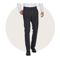 Ein Mann trägt schwarze, lockere Hosen, kombiniert mit einem weißen Hemd und schwarzen Schuhen.
